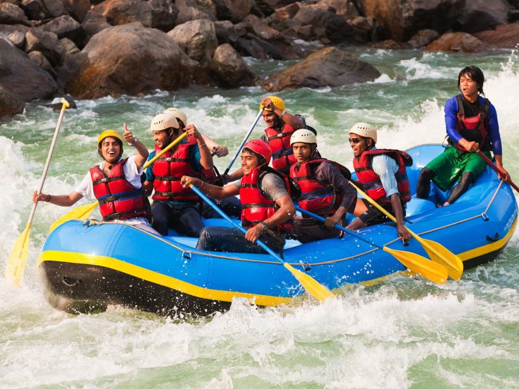 River rafting in Rishikesh – group on blue raft in Ganga rapids